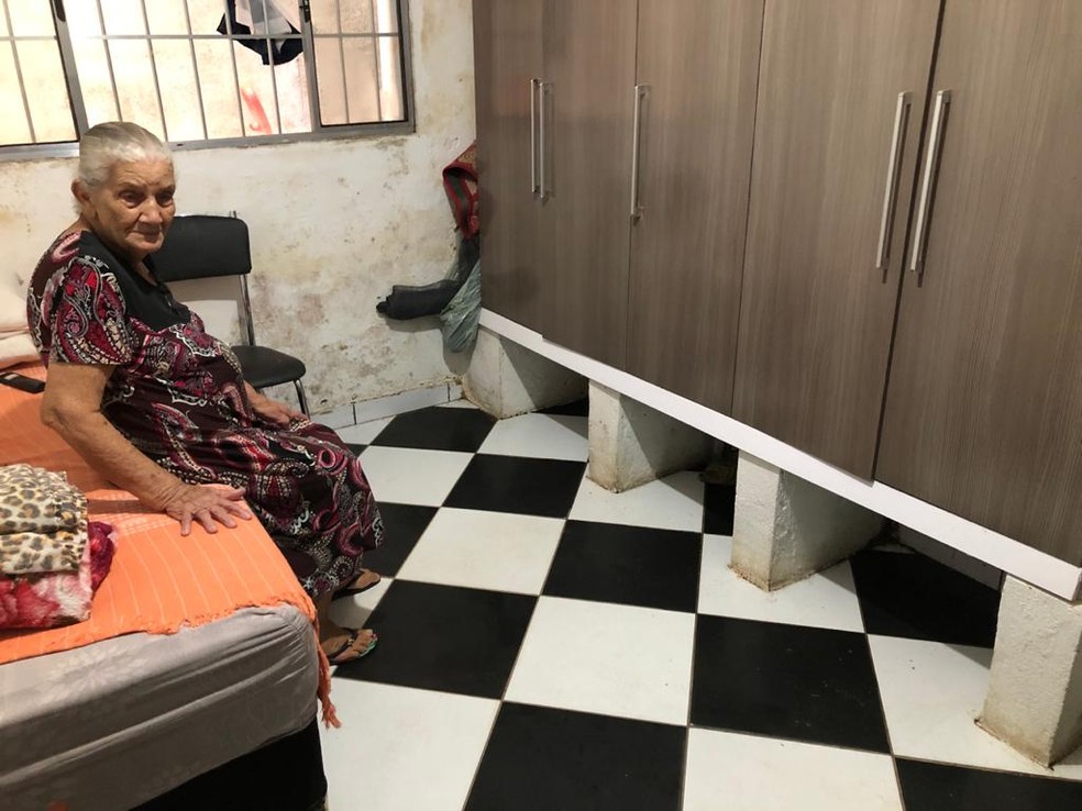 Maria da Cruz, de 86, reclama que dorme na cama ainda úmida. De tanto perder móveis, ela coloca o armário num nível acima do chão. — Foto: Paula Paiva Paulo/G1