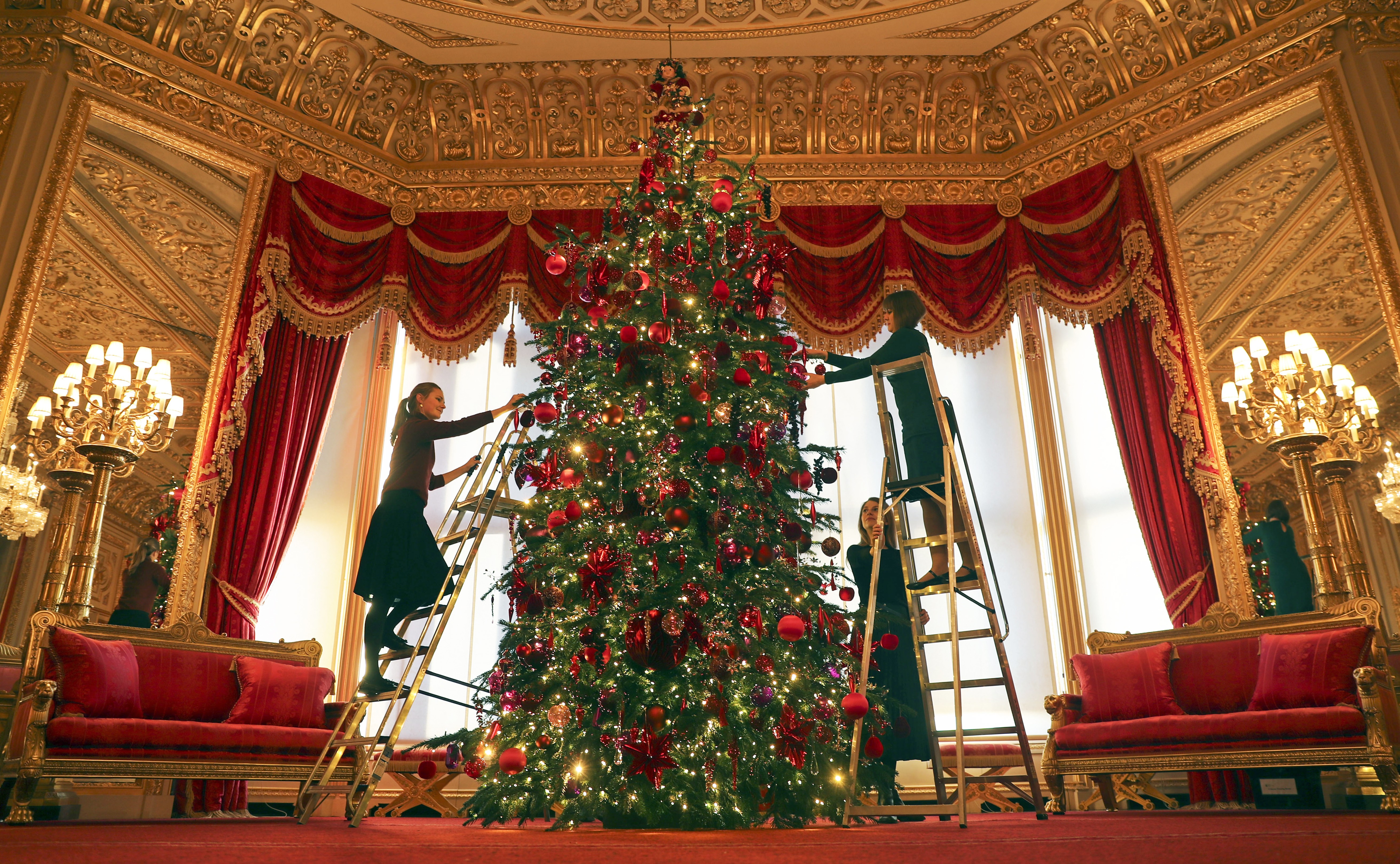 Royal Collection Trust members of staff put the finishing touches to a 15ft Christmas tree in the Crimson Drawing Room at Windsor Castle, Berkshire. (Photo by Steve Parsons/PA Images via Getty Images) (Foto: PA Images via Getty Images)
