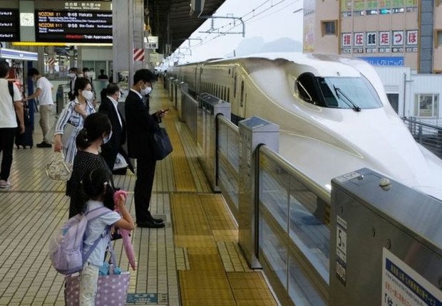 Passageiros ao lado de trem-bala no Japão; sistema ferroviário do país é conhecido por sua pontualidade (Foto: GETTY IMAGES via BBC NEWS)