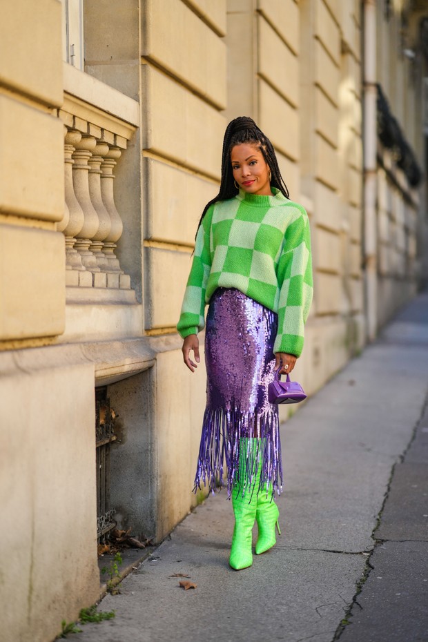 PARIS, FRANCE - JANUARY 14: Ellie Delphine wears gold large earrings, a pale green and dark green checkered print pattern oversized high neck fluffy pullover, a purple shiny sequined fringed midi skirt, a purple shiny leather zipper small handbag, neon gr (Foto: Getty Images)