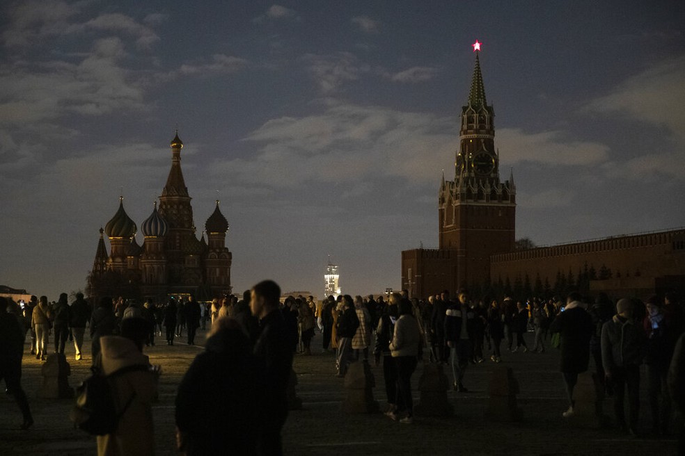 Visitantes tiram fotos na Praça Vermelha, em Moscou, das luzes apagadas do Kremlin e da Catedral de São Basílio, neste sábado (27), na Hora do Planeta 2021 — Foto: Pavel Golovkin/AP Photo