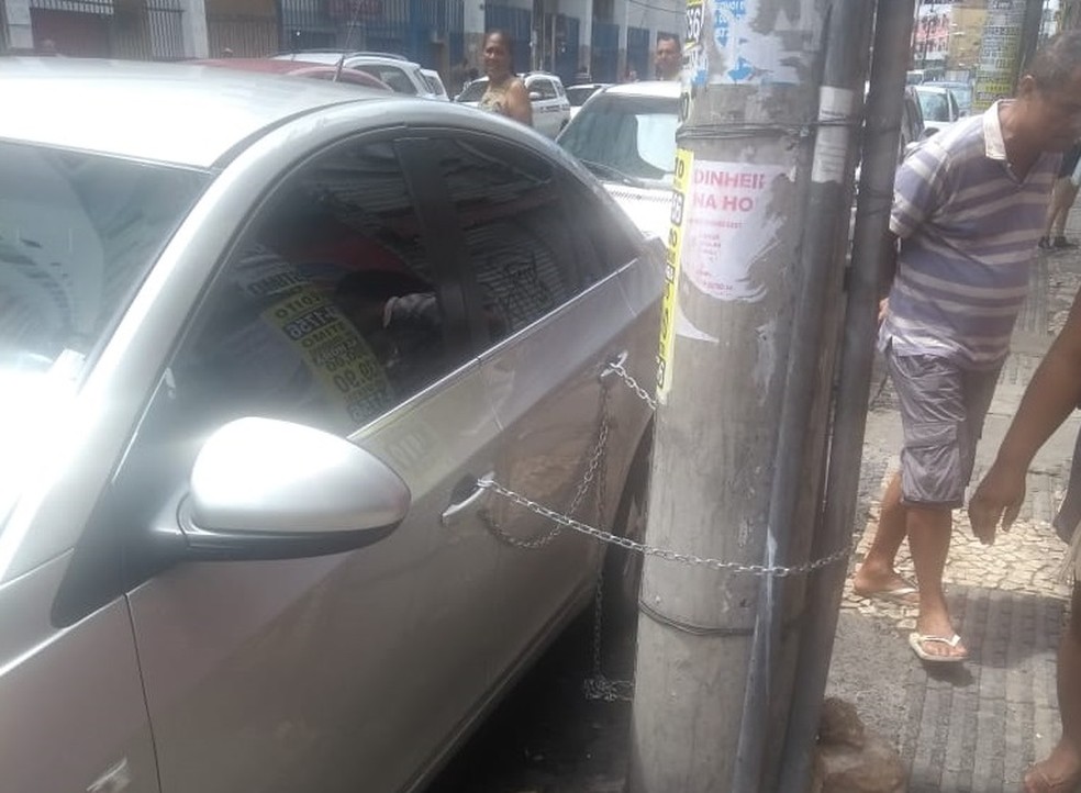 Morador de prÃ©dio de Salvador acorrenta carro a poste (Foto: Transalvador)