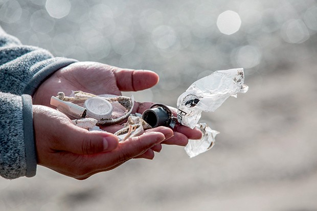 Miranda Wang examina lixo plástico em praia da região (Foto: Pierre Verdi/ AFP/ Divulgação )