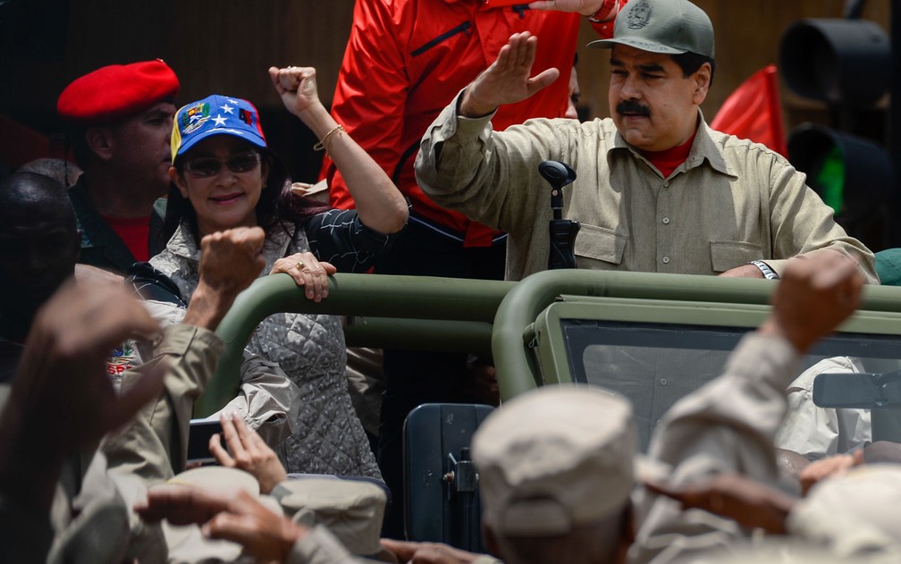O presidente venezuelano Nicolás Maduro, ao lado de sua mulher Cilia Flores, acena ao chegar às comemorações do sétimo aniversário da Milícia Bolivariana, em frente ao Palácio Miraflores, em Caracas, na segunda-feira (17) (Foto: Federico Parra/AFP)