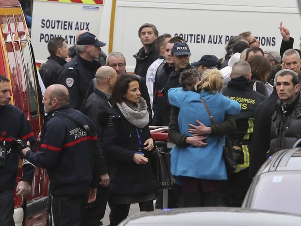 Pessoas se abraçam em frente à sede da revista satírica 'Charlie Hebdo', após ataque terrorista em Paris (Foto: Remy de la Mauviniere/AP)