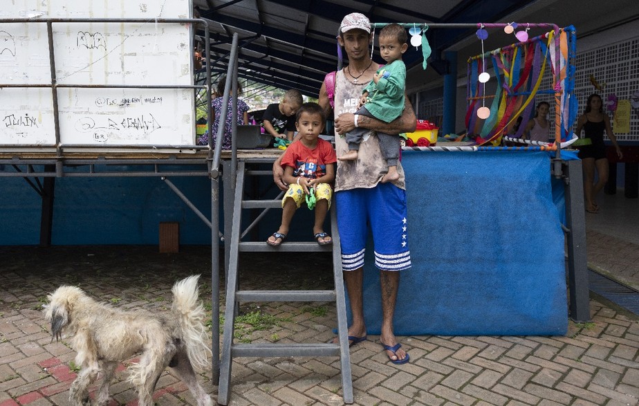 Thiago Aparecido com os filhos, que salvou de casa inundada escapando pelo teto