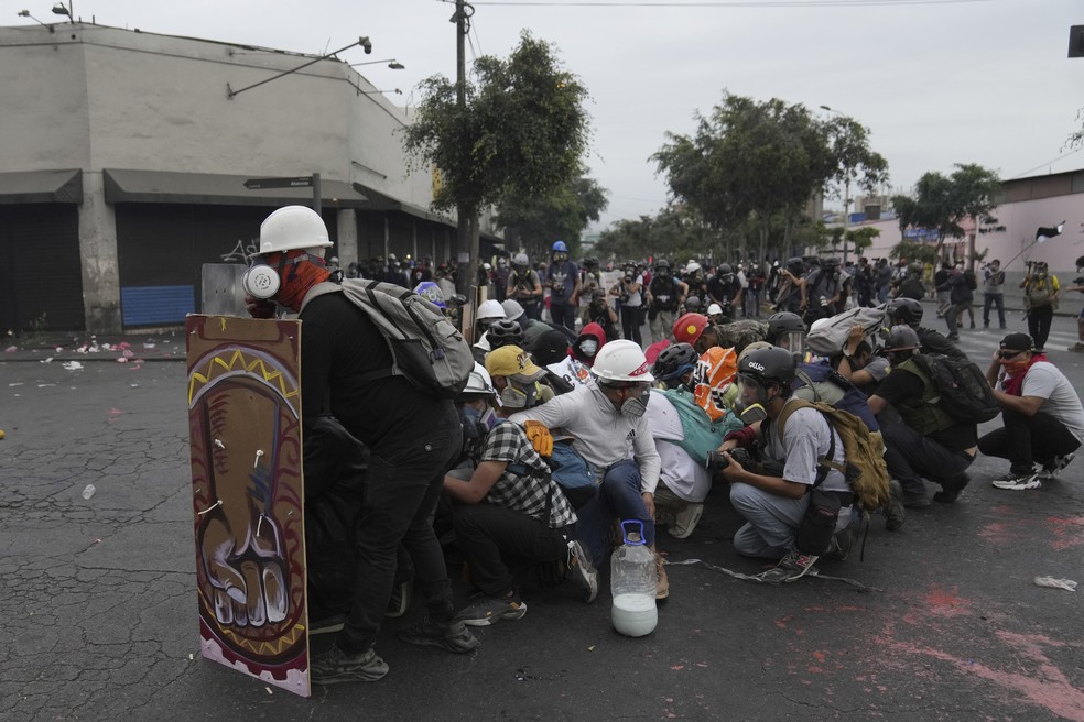 Manifestantes anti-governo se refugiam atrás de um escudo durante confrontos com a polícia, em Lima, Peru, em 28 de janeiro de 2023 — Foto: Martin Mejia/AP