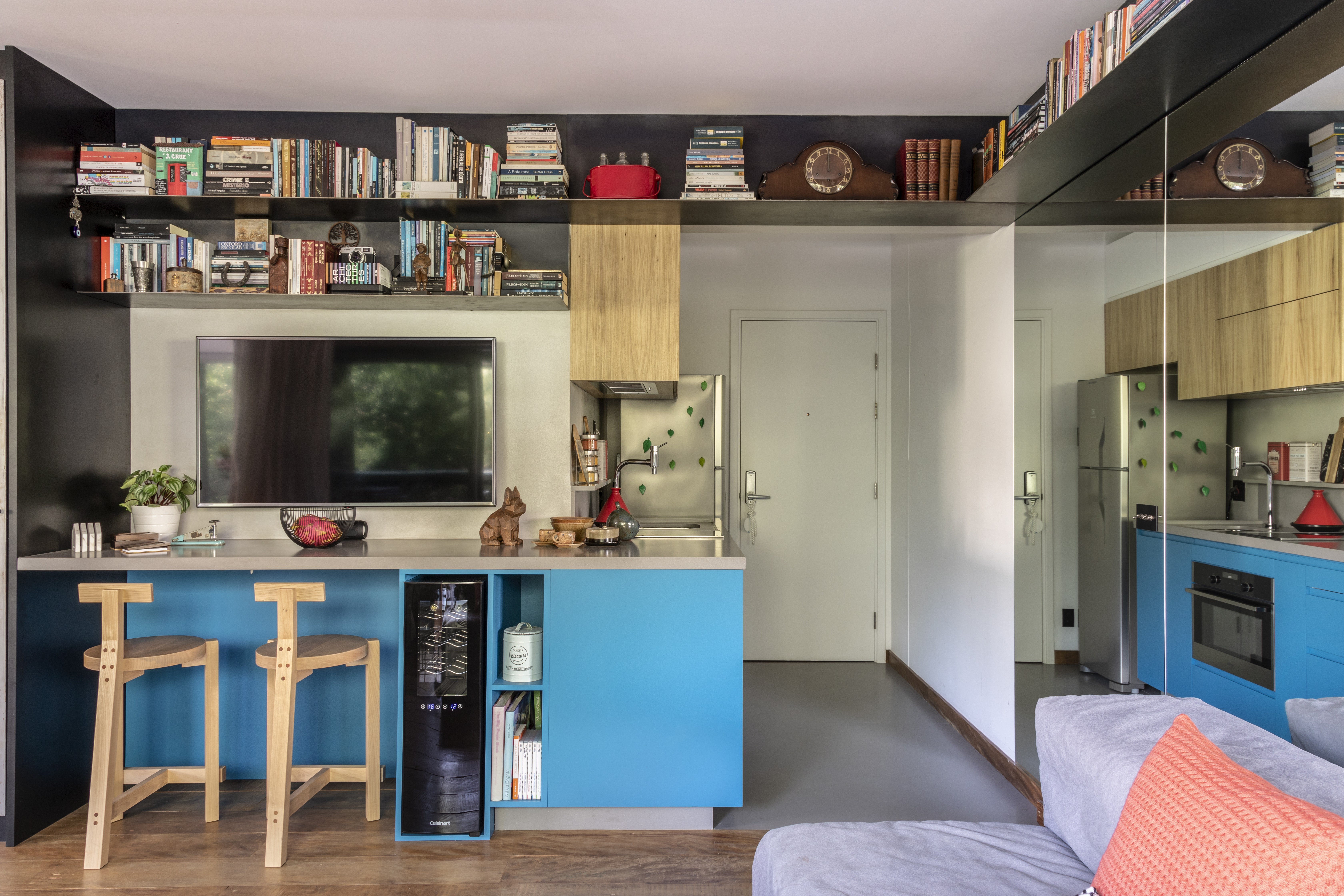 El banco Blue Caesarstone Concrete Sleek es un destaque en un departamento de 44 m² que prioriza la integración de los ambientes.  Los estantes para libros dan funcionalidad y decoran el apartamento.  El espejo en la pared ayuda a aumentar la sensación de espacio en la propiedad (Foto: Evelyn Muller)
