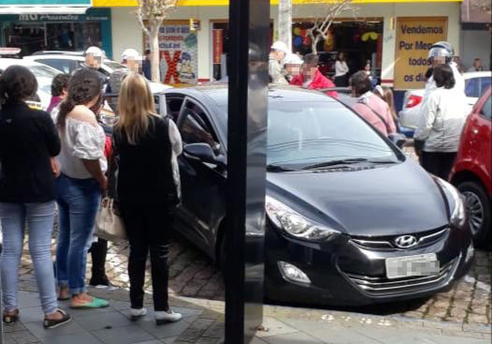 Populares cercam o carro para retirar menina de 7 anos que estava trancada. — Foto: Arquivo pessoal