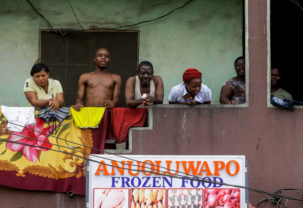 Moradores de um prédio olham da varanda em Lagos, na Nigéria, em 31 de março, enquanto a cidade enfrenta um bloqueio de duas semanas com os moradores instruídos a ficarem em suas casas para impedir a propagação do novo coronavírus — Foto: Sunday Alamba/AP