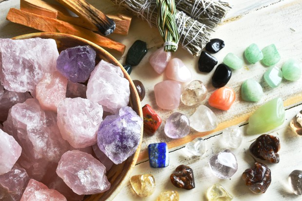 A top view image of a bowl of rose quartz crystals with several other healing crystal and smudge sticks. (Foto: Getty Images/iStockphoto)