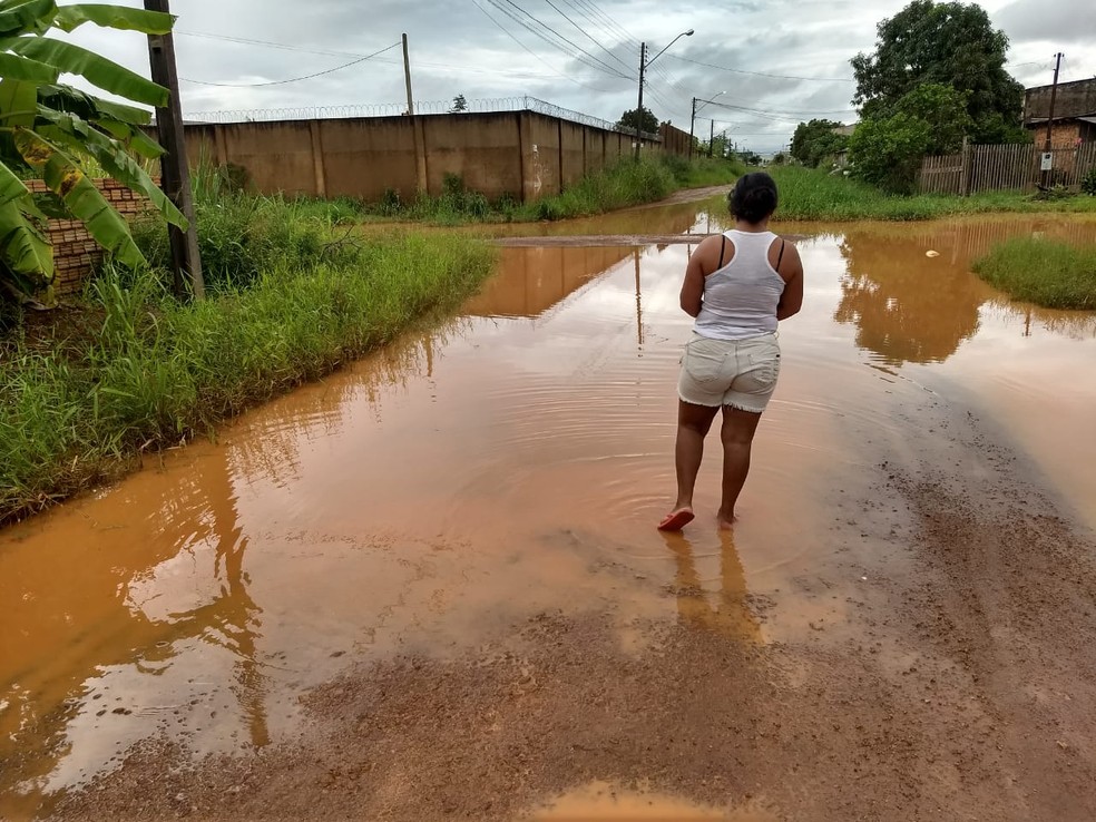 Moradora Aline Santos enfrentou água quase no joelho ao sair de casa para comprar pão no bairro Lagoa. — Foto: Diêgo Holanda/G1