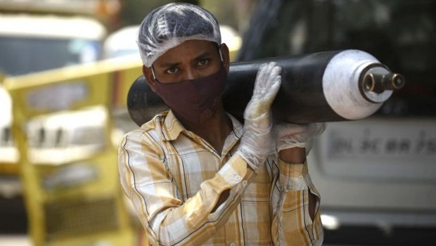 Uma pessoa esperando para reabastecer seu cilindro de oxigênio vazio em Gurgaon, Índia; cena aconteceu tanto no Brasil quanto no pais asiático (Foto: Getty Images)