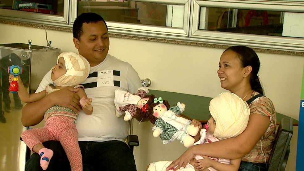 Com as filhas no colo, Diego e Débora Freitas seguram as 'bonecas siamesas' em Ribeirão Preto — Foto: Cláudio Oliveira/EPTV