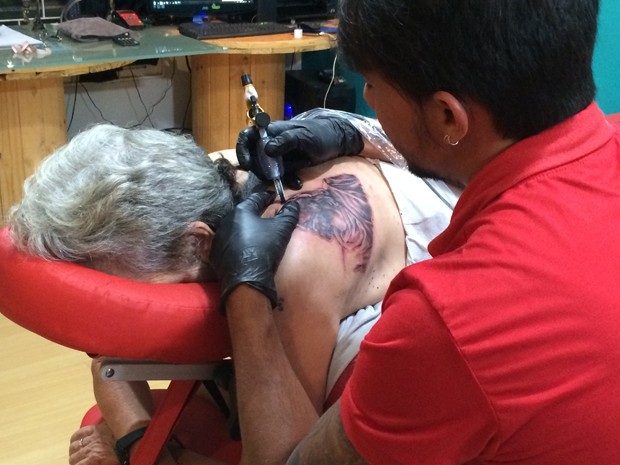 Marieta conclui uma tatuagem do rosto de Jesus, a última das 16 (Foto: Felipe Gibson/G1)
