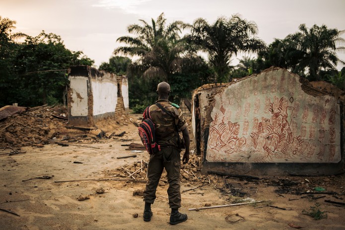 Integrante das forças armadas congolesas é fotografado ao lado de um prédio queimado na cidade Yumbi, na República Democrática do Congo, em 1º de fevereiro de 2019  — Foto: Alexis Huguet / AFP