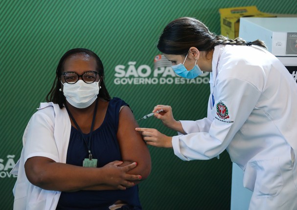 SAO PAULO, BRAZIL - JANUARY 17: Nurse Monica Calazans (54) receives the first CoronaVac vaccination shot in Brazil from Disease Control nurse and Master of Public Health at Santa Casa de Sao Paulo, Jessica Pires de Camargo, at Hospital das Clinicas of the (Foto: Getty Images)