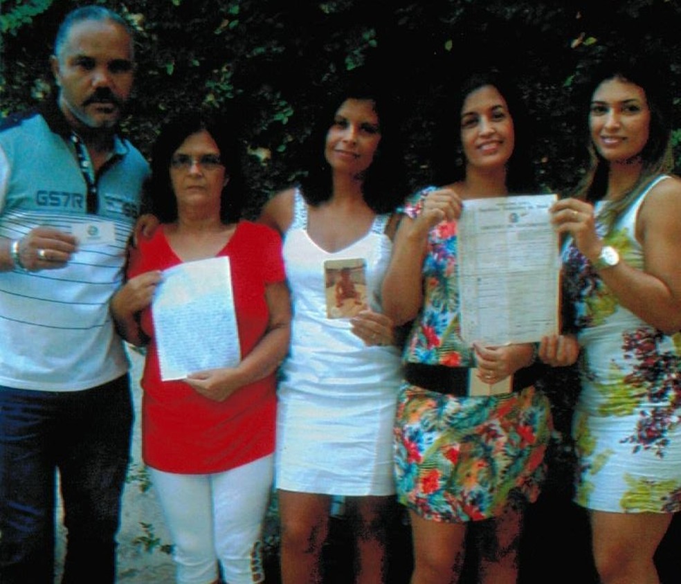 Em 2015, Marlene (de vermelho) ao lado das três filhas e do genro segurando carta com pedido de ajuda para reencontrar Michele e Queli — Foto: Arquivo Pessoal