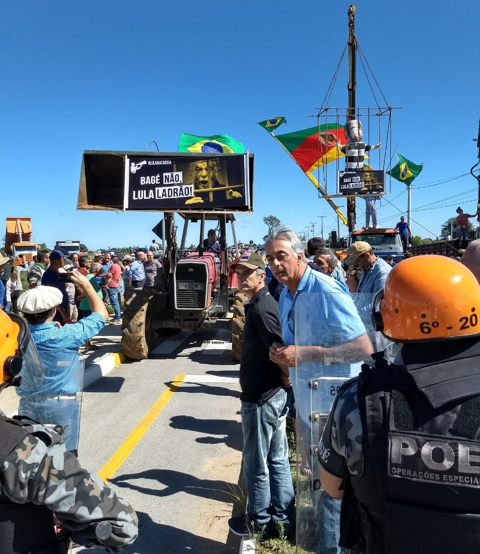 Manifestantes com faixas e boneco do ex-presidente protestam contra caravana (Foto: Barbara Lignon/RBS TV)