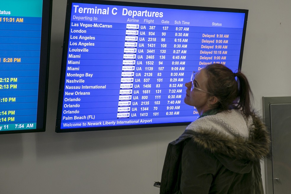 Passageira verifica voos atrasados e cancelados no aeroporto de Newark na quarta-feira, 11 de janeiro de 2022 — Foto: Ted Shaffrey/AP