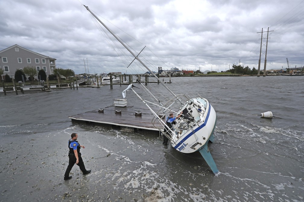 Policiais fazem vistoria em barco a vela em busca de ocupantes depois de o furacão Dorian passar pela costa da Carolina do Norte, nos Estados Unidos, nesta sexta-feira (6). — Foto: Tom Copeland/AP