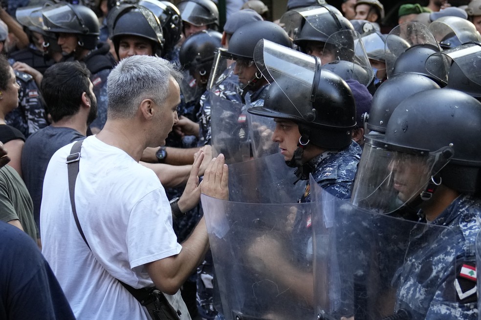 Civis diante de policiais libaneses durante protesto no Líbano — Foto: Hussein Malla/AP