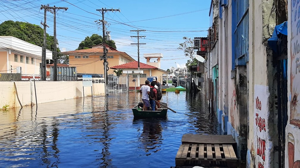 Trabalhadores usam canoas para passar pelo centro de Manaus, atingido pelo cheia do Rio Negro — Foto: Eliana Nascimento/G1