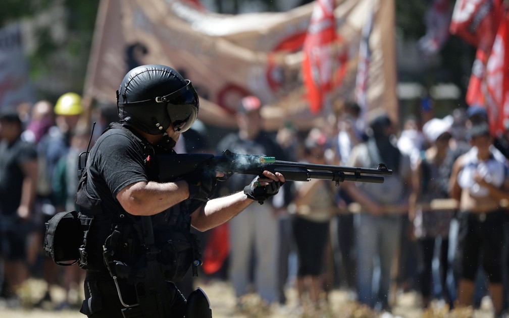 Policial dispara balas de borracha em manifestantes durante confrontos em frente ao Congresso Nacional em votação pela reforma da previdência, em Buenos Aires, na Argentina, na segunda-feira (18) (Foto: AP Photo/Natacha Pisarenko)