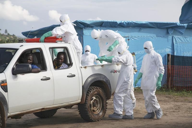 Funcionários de um centro médico usam roupas protetoras para enterrar uma paciente que morreu de ebola (Foto: efe)