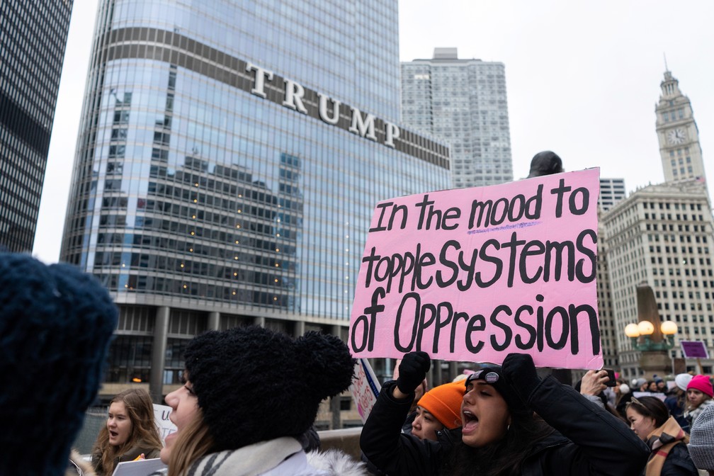 'A fim de derrubar sistemas de opressão': manifestante segura cartaz em Marcha das Mulheres neste sábado (18) em frente ao Trump Hotel, de propriedade do presidente norte-americano, em Chicago — Foto: Max Herman/Reuters