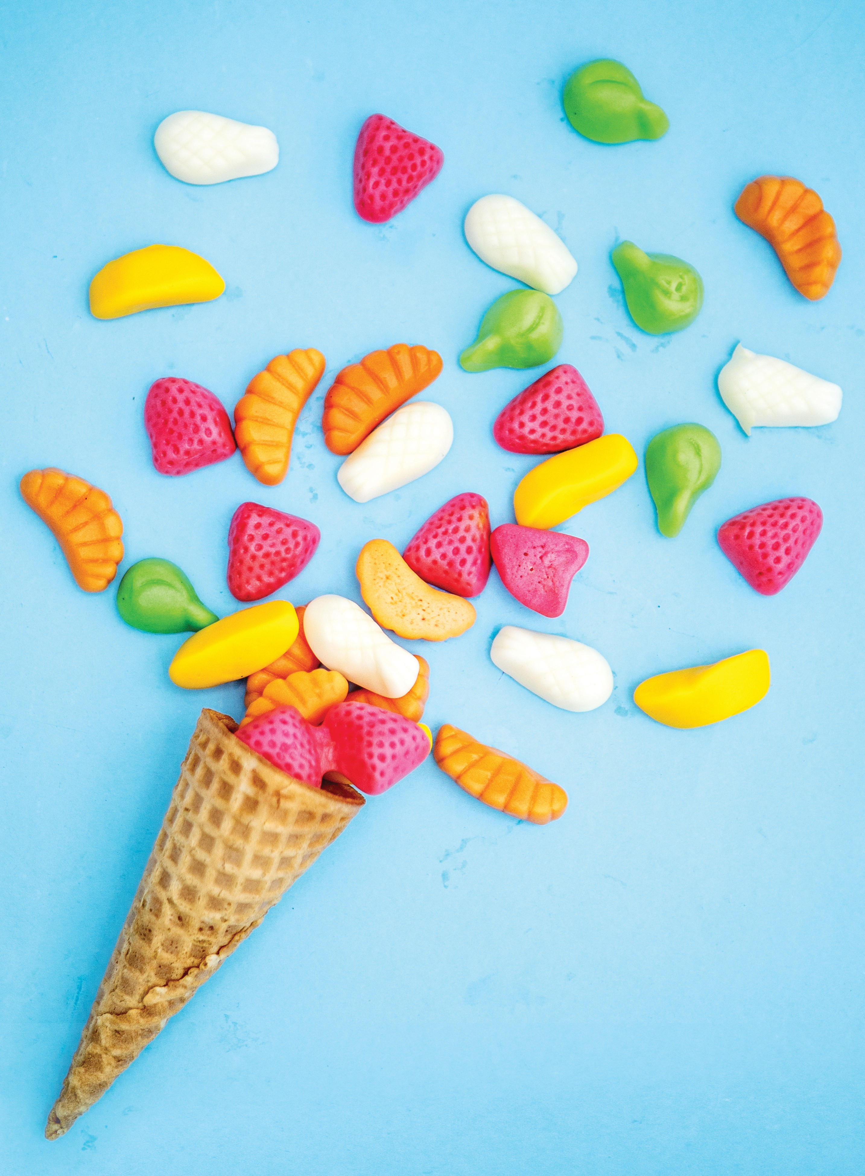 Colorful explosion of candies in ice cream cornet on turquoise background. (Foto: Getty Images)