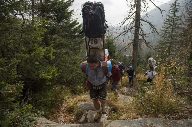Enquanto você 'morre' para subir a montanha, um sherpa carregado de malas passa correndo como se não fosse nada (Foto: Getty Images via BBC News Brasil)