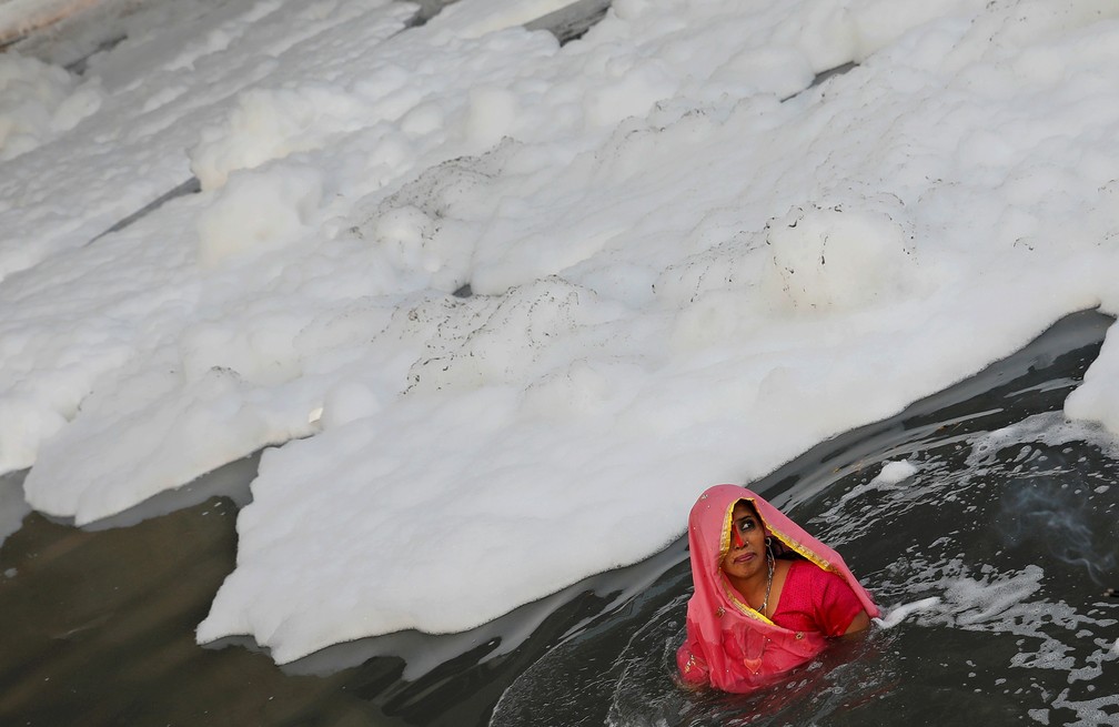 10 de novembro - Uma mulher hindu faz um ritual de adoração ao deus Sol em meio à espuma de poluição que cobre o rio Yamuna durante o festival religioso hindu de Chhath Puja em Nova Delhi, na Índia    — Foto: Adnan Abidi/Reuters/Arquivo 