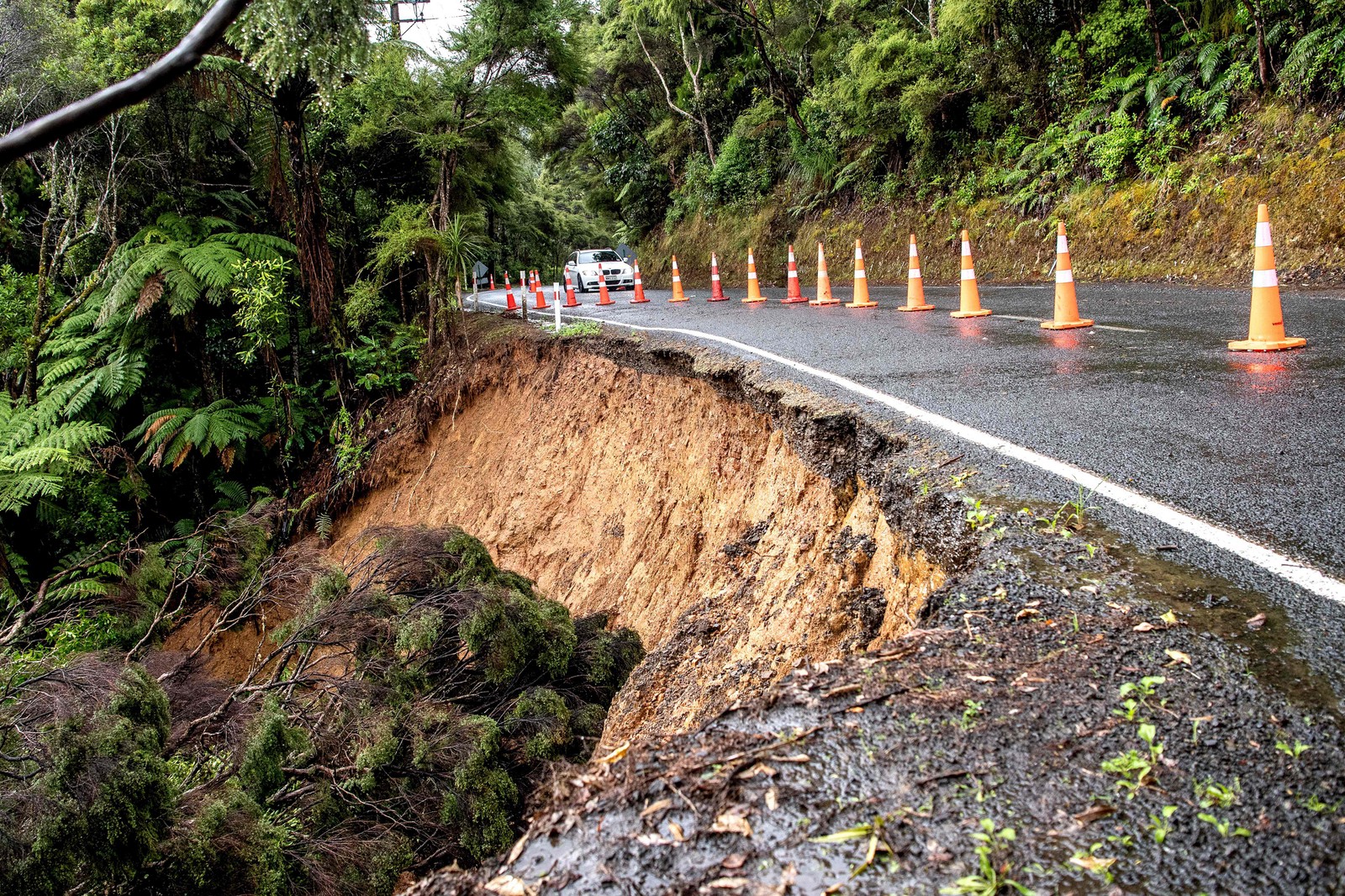 Carro trafega por estrada danificada após fortes chuvas nos arredores de Auckland, Nova Zelândia — Foto: Ivan Tarlton / AFP