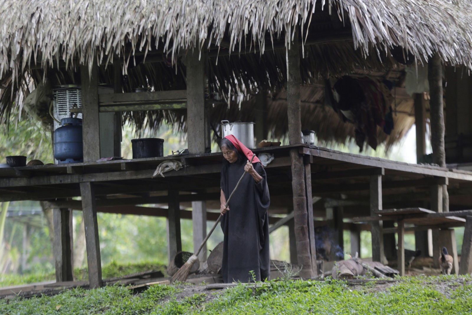 Uma anciã ashaninka varre a frente de sua casa ao amanhecer  — Foto: Domingos Peixoto / Agência O Globo