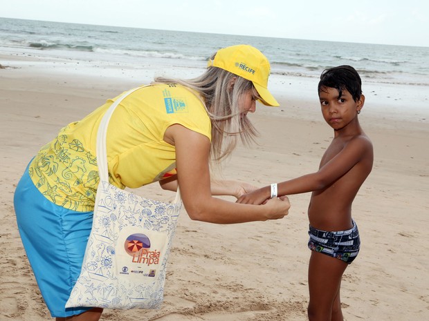 Promotora coloca a pulseirinha de identificação no brasiliense João Gabriel, que veio à praia com as tias. (Foto: Ivaldo Bezerra / Lumen)