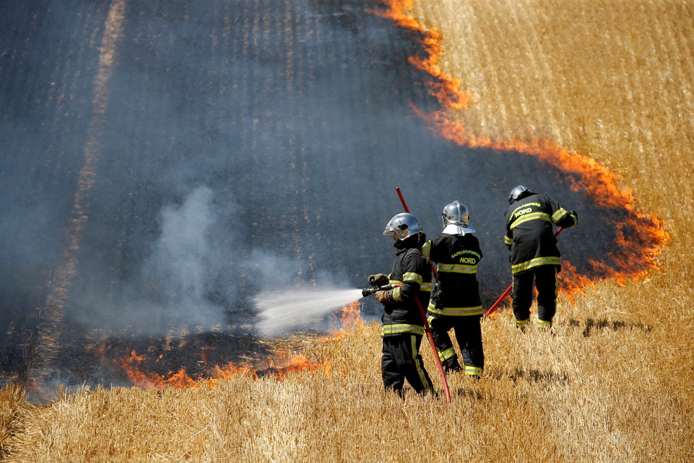 Bombeiros combatem um incêndio em um campo de trigo em chamas durante a temporada de colheita em Aubencheul-au-Bac, na França, em 21 de julho — Foto: Pascal Rossignol/Reuters