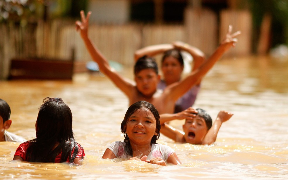 Crianças brincam na enchente do Rio Acre no bairro do Taquari, em Rio Branco. A cheia superou a marca histórica registrada em 1997, chegando a 17,88 metros. — Foto: Raimundo Pacco/Frame/Estadão Conteúdo