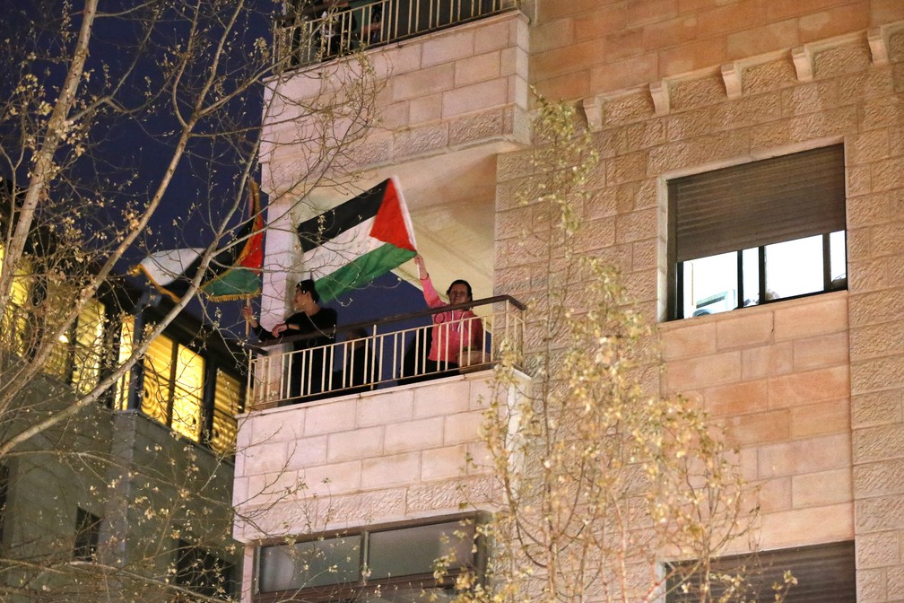Palestinos comemoram o Dia da Terra Palestina agitando bandeiras de suas varanda em Ramallah, na Cisjordânia ocupada, em 30 de março, em vez das marchas de rua que foram canceladas devido à pandemia do COVID-19 — Foto:  Abbas Momani/AFP