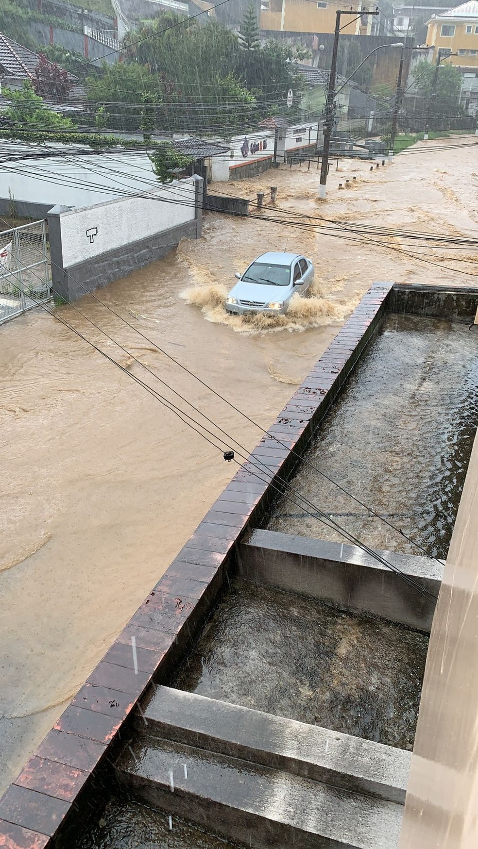 Motorista precisa reduzir a velocidade para conseguir atravessar a rua alagada — Foto: Redes sociais 