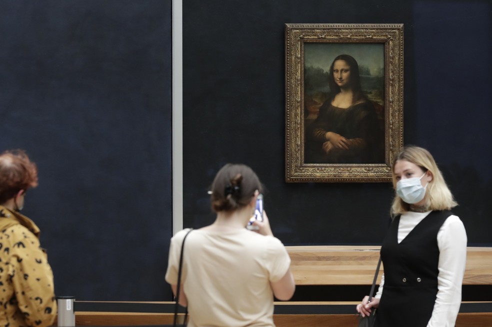 Visitantes posam em frente à Mona Lisa de Leonardo da Vinci no museu do Louvre — Foto: Thibault Camus/AP