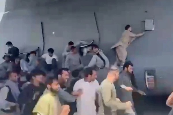 Cidadãos afegãos tentando entrar um avião em fuga de Cabul (Foto: Reprodução)