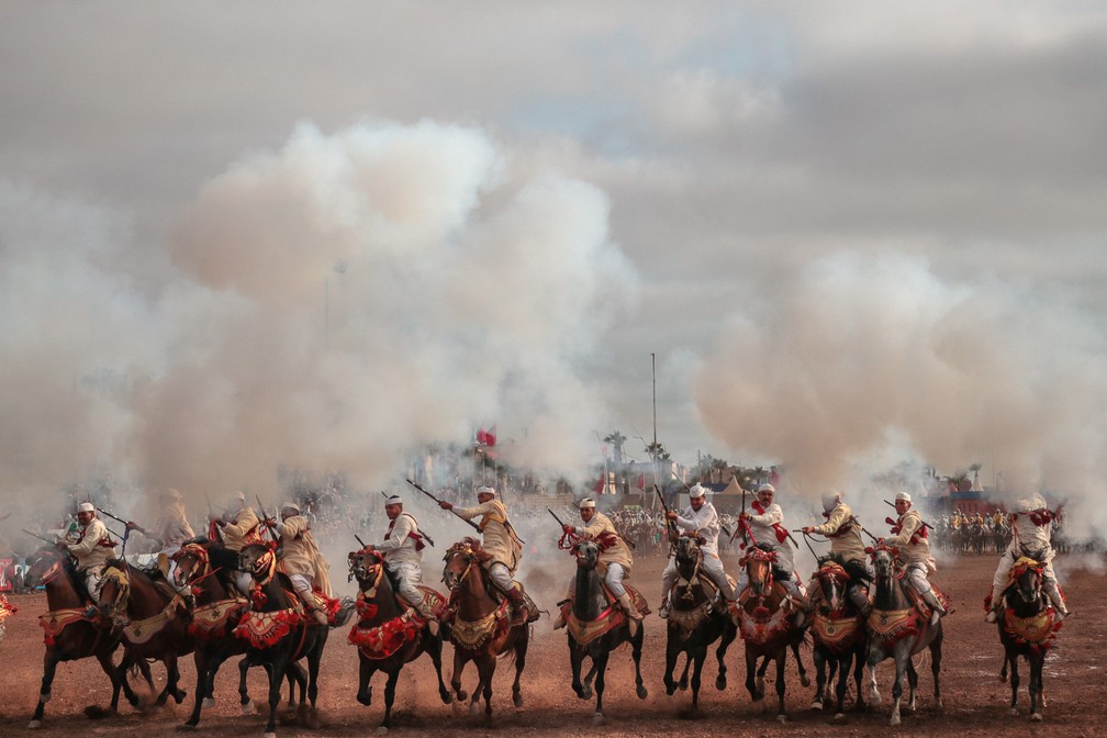 25 de julho - Trupe dá tiros de rifle durante cavalgada na 'Tabourida', uma apresentação tradicional com cavalos também chamada de 'Fantasia' na cidade costeira de El Jadida, no Marrocos — Foto: Mosa'ab Elshamy/AP