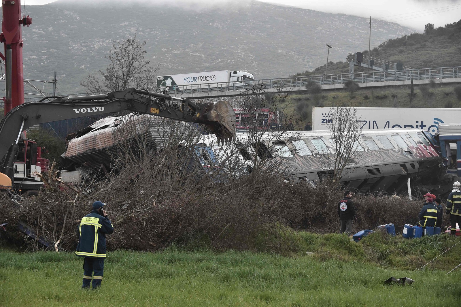A polícia e as equipes de emergência vasculham os destroços de um vagão esmagado após um acidente de trem no vale Tempi, perto de Lárissa, Grécia, em 1º de março de 2023 — Foto: Sakis Mitrolidis / AFP