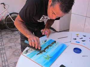 Antonio Marcos pintando uma paisagem com um rodo de pia (Foto: Mariane Rossi/G1)