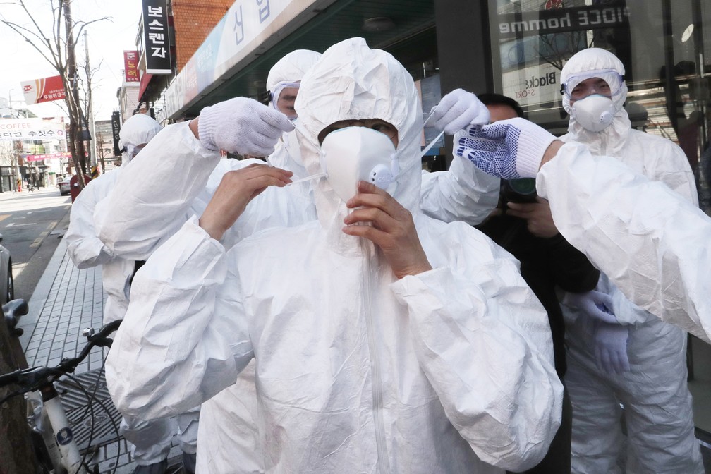 Agentes de saúde usam máscaras faciais para aplicar desinfetante como precaução contra o novo coronavírus nesta quinta (27) em Seul, na Coreia do Sul. — Foto: Ahn Young-joon/AP