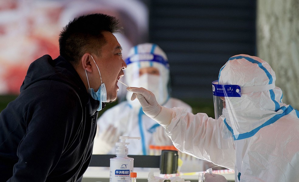 Homem tem amostra de saliva coletada para teste de Covid-19 em Pequim, na China, na segunda-feira (16). — Foto: Noel Celis / AFP