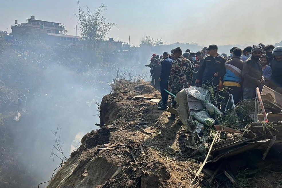 Equipes de resgate trabalham no local do acidente no Nepal neste domingo (15) — Foto: Krishna Mani Baral/AFP