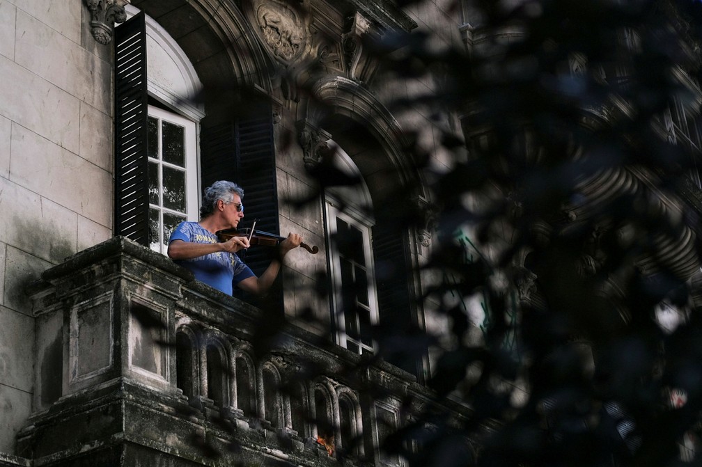 Adelmo Carvalho, de 55 anos, toca violino na varanda durante o isolamento para evitar a propagação da doença por coronavírus (COVID-19) no Rio de Janeiro  — Foto: Ricardo Moraes/Reuters