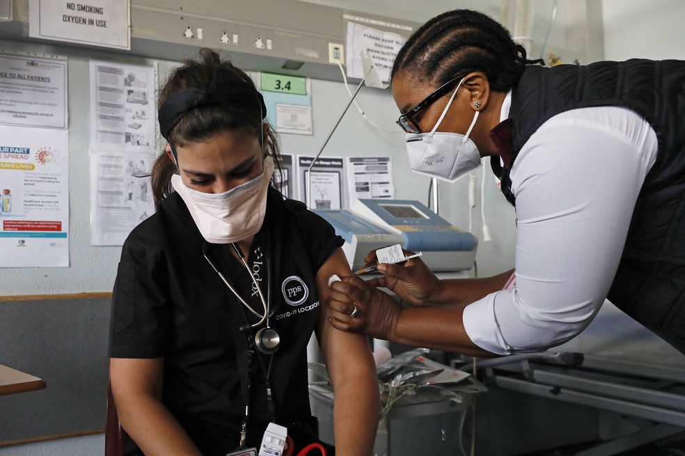 Médica recebe dose da vacina da Johnson contra a Covid-19 de enfermeira em Pretória, na África do Sul, no dia 17 de fevereiro. — Foto: Phill Magakoe / AFP